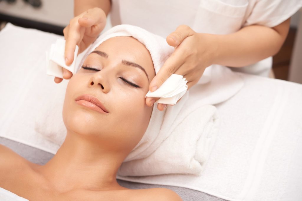 Esthéticienne réalisant un soin du visage en cabine
